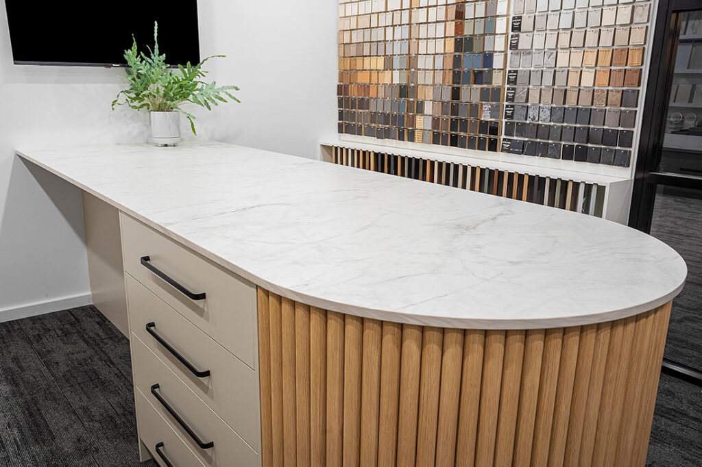 Kitchen Counter Featuring Stone Benchtops, With a Television Displayed on the Wall Above — Vivid Stoneworks in Thornton, NSW